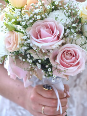 Bride holds a bridal bouquet with pink roses