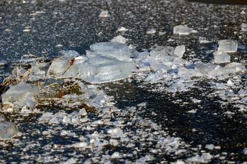 Zimowy widok na zamarzniętą wodę z kawałkami lodu. 
