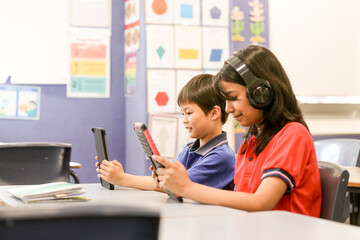 students in the classroom with headphones and iPads