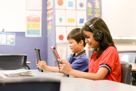 students in the classroom with headphones and iPads