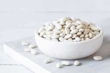 Uncooked dried white haricot beans in bowl or spoon on table. Heap of legume haricot bean background ( Phaseolus vulgaris )