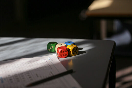 dice sitting on a desk in the shadows in a classroom