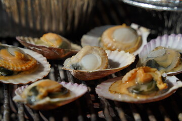 various types of clams are grilled on a grill and then dipped in seasoning and eaten.