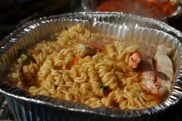 Instant ramen boiled in an aluminum disposable container with seafood such as crab