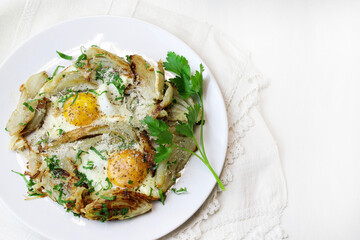 Uova fritte fatte in casa e finocchio con erbe in una padella di ferro su sfondo bianco. Cibo sano e vegetariano. Vista dall'alto. - 765649093