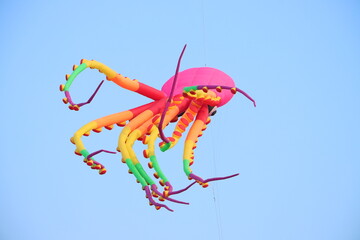 Colorful octopus kite flying in blue sky. Happy childhood moments.