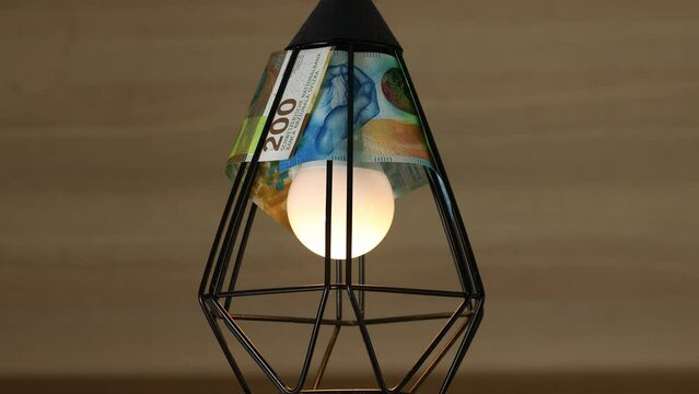Switzerland energy, Increase in electricity prices in Switzerland, Economic concept, Turning on and off the light lampshade made of Swiss francs