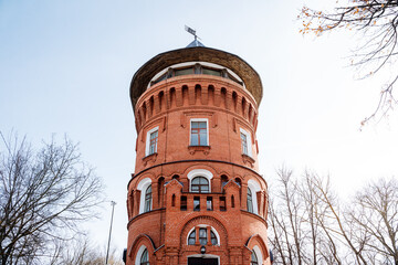 A red brick water tower with a dome, surrounded by trees and against the sky