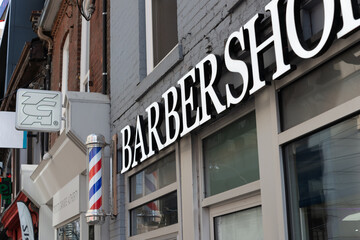 Fototapeta premium exterior building facade barber pole and sign of Tower Barber Shop located at 231 Queen Street West in Toronto, Canada