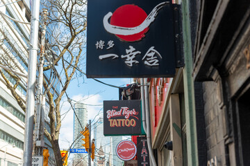 Fototapeta premium signs on the south side of Queen Street West in Toronto, Canada (including The Blind Tiger Tattoo located at 247 Queen Street West 2nd Floor)