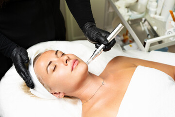 Microneedle RF lifting procedure. A cosmetologist performs a facial rejuvenation procedure on a...