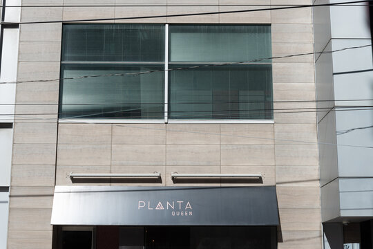 exterior building facade and sign of PLANTA, a vegan restaurant, located at 180 Queen Street West in Toronto, Canada