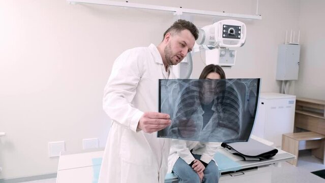 A male medical doctor discusses the results of an X-ray image with a young female patient. Concept of medical technologies, treatment and health status.