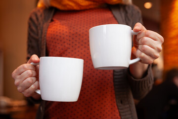 The closeup of the girl's hands holding two white cups of hot coffee. Selective soft focus - 765693635