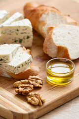Homemade organic white cheese served with crispy bread, walnut and olive oil on wooden board on the table. Healthy food, snack and eating. - 765694618