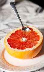 Half of a cut fresh grapefruit on a plate with a spoon. The concept of a healthy lifestyle. Directly above - 765695419