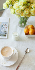 A cup of delicious morning coffee with organic yogurt, apricots and a bouquet of cream roses in the background. Selective soft focus - 765695484