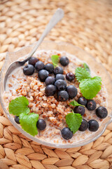 Buckwheat porridge with organic blueberries in a glass plate on a straw table mat. closeup - 765696013