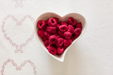 Top view of dried raspberries in a plate in the shape of a heart. - 765696464