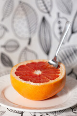 Half of a cut fresh grapefruit on a plate with a spoon. The concept of a healthy lifestyle. - 765696882