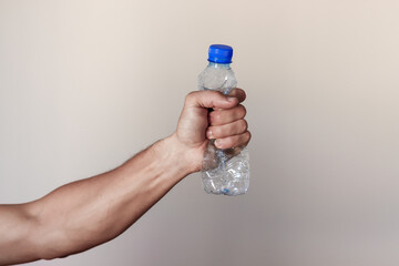 Hand squeezing Plastic Bottle representing movement against pollution and for recycling