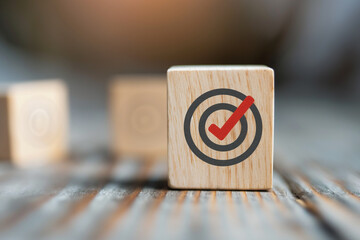 Wooden block with a red check mark on a target icon. Achievement, goal, or success concept.