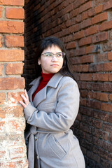 A woman in a gray coat standing between two brick walls	