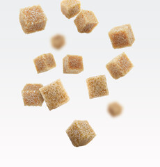 Brown cane sugar cubes falling on white background