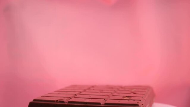 A bar of pink ruby chocolate with freeze-dried strawberries and almonds close-up. A healthy dessert based on berries and nuts
