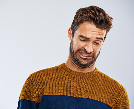 Man, frown and facial expression in studio for disgust and regret for attitude, emotion and mood. Male model and young person and isolated with face gesture or grimace for oops on white background