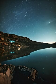 the night sky is reflected in the still water of a lake