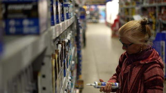 Closeup of woman comparing products in hardware store trying to make decision. Concept of home remodeling shopping experience.