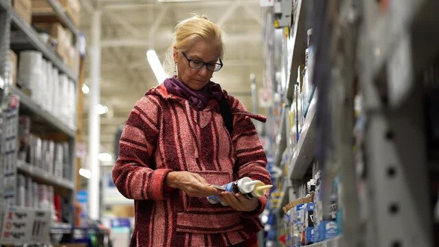 Closeup of woman comparing products in hardware store trying to make decision. Concept of home remodeling shopping experience.