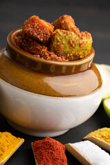 Homemade Mango Pickle or aam ka achar Kairi Loncha stored or preserved in China clay pot with Ingredients.