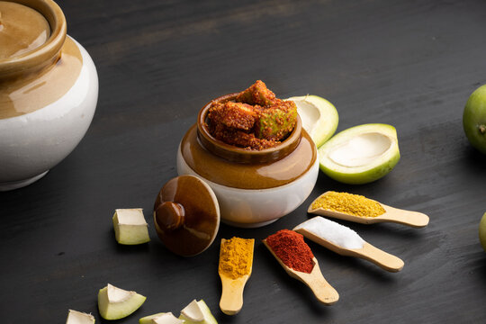 Homemade Mango Pickle or aam ka achar Kairi Loncha stored or preserved in China clay pot with Ingredients.