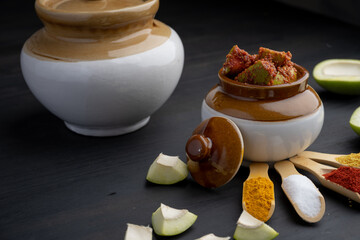 Homemade Mango Pickle or aam ka achar Kairi Loncha stored or preserved in China clay pot with...