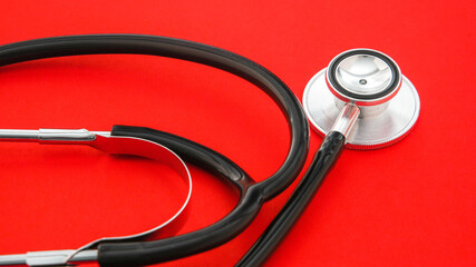 Professional stethoscope on a red  background signifying medical examination and healthcare