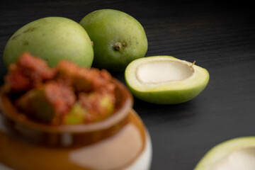 Homemade Mango Pickle or aam ka achar Kairi Loncha stored or preserved in China clay pot with Ingredients.