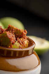 Homemade Mango Pickle or aam ka achar Kairi Loncha stored or preserved in China clay pot with...