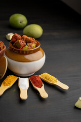 Homemade Mango Pickle or aam ka achar Kairi Loncha stored or preserved in China clay pot with Ingredients.