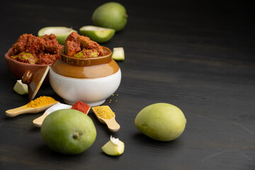 Homemade Mango Pickle or aam ka achar Kairi Loncha stored or preserved in China clay pot with Ingredients. - obrazy, fototapety, plakaty