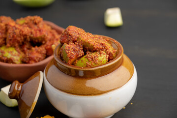 Homemade Mango Pickle or aam ka achar Kairi Loncha stored or preserved in China clay pot with...