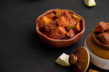 Homemade Mango Pickle or aam ka achar Kairi Loncha stored or preserved in China clay pot with...