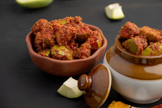 Homemade Mango Pickle or aam ka achar Kairi Loncha stored or preserved in China clay pot with Ingredients.