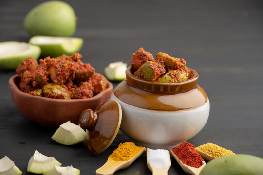 Homemade Mango Pickle or aam ka achar Kairi Loncha stored or preserved in China clay pot with Ingredients.