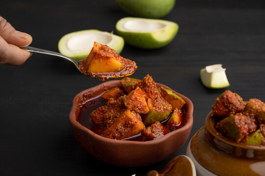Homemade Mango Pickle or aam ka achar Kairi Loncha stored or preserved in China clay pot with Ingredients.