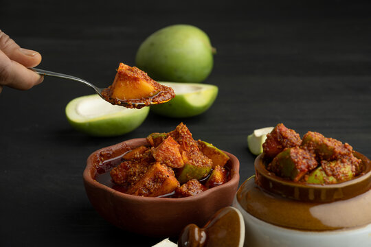 Homemade Mango Pickle or aam ka achar Kairi Loncha stored or preserved in China clay pot with Ingredients.