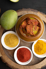 Homemade Mango Pickle or aam ka achar Kairi Loncha stored or preserved in China clay pot with Ingredients.