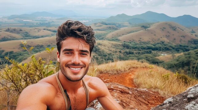 A man is smiling and posing for a picture on a mountain
