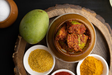 Homemade Mango Pickle or aam ka achar Kairi Loncha stored or preserved in China clay pot with...